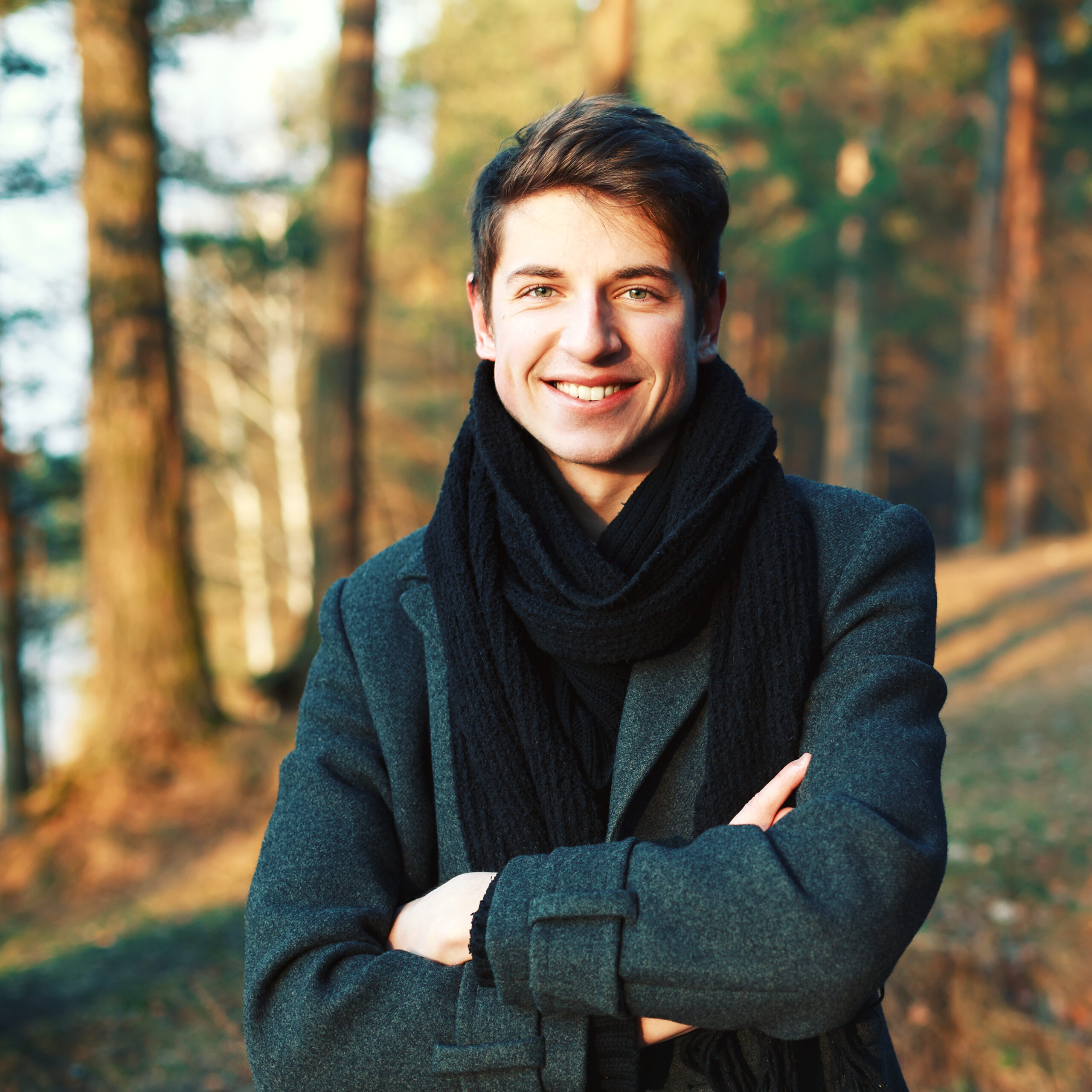 smiling-young-man-with-crossed-arms-outdoors